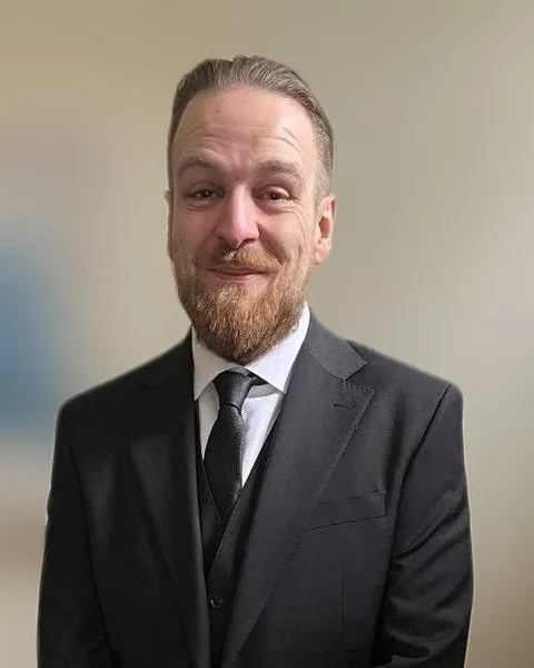 Malcolm Fellowes, smiling, in a dark three-piece suit and tie