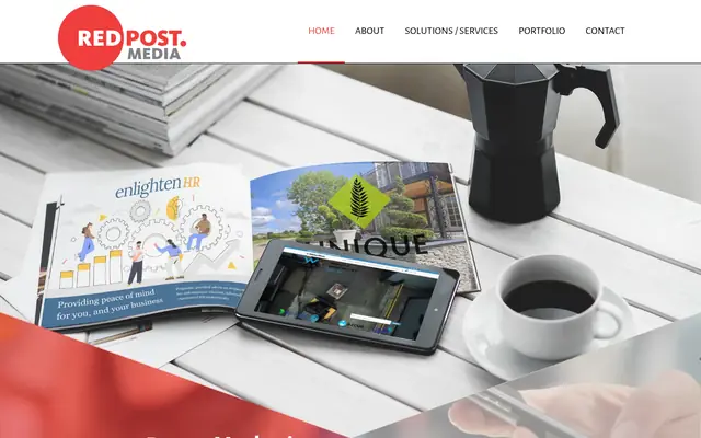 Redpost Media homepage: the Redpost logo above a desk with printed brochures and a tablet